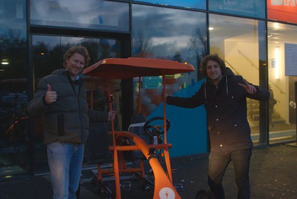 Alexander Stolze en Tijs Koedam bij de oranje Op De Fiets Met fiets pratend over vitaliteitsmanagement en wellbeing